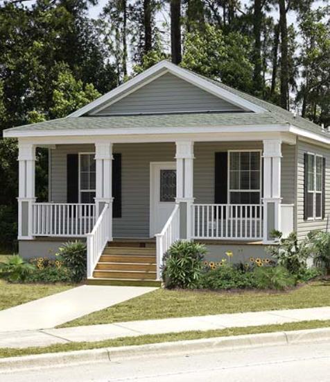 A small manufactured home with a porch on land