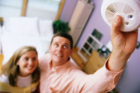Photo of a man reaching up to install a smoke detector