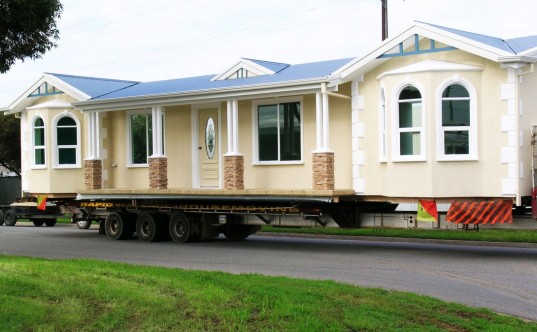 A photo of a manufactured home being transported on a truck